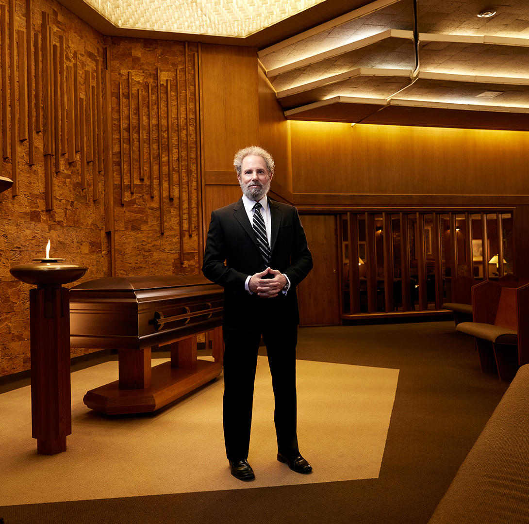 Funeral Director standing in front of a coffin in a celebration of life chapel.